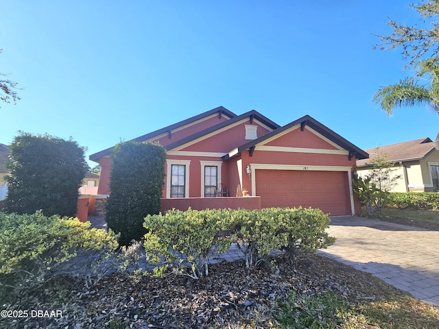 ranch-style home with stucco siding, an attached garage, and driveway