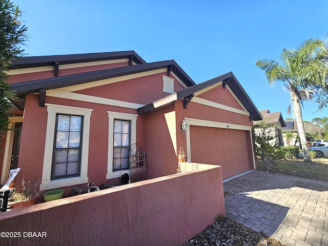 view of front of house featuring stucco siding, a garage, driveway, and fence