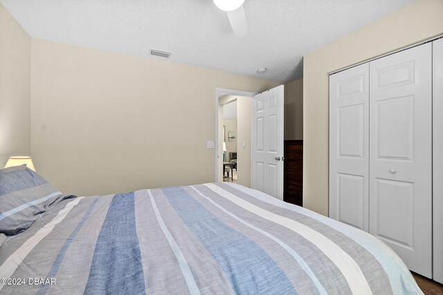 bedroom featuring a textured ceiling, ceiling fan, and a closet