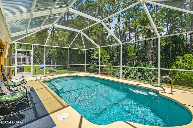 view of pool with glass enclosure and a patio area