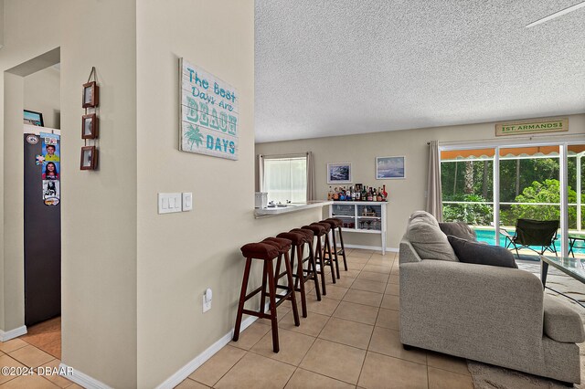 living room with a textured ceiling and light tile patterned flooring