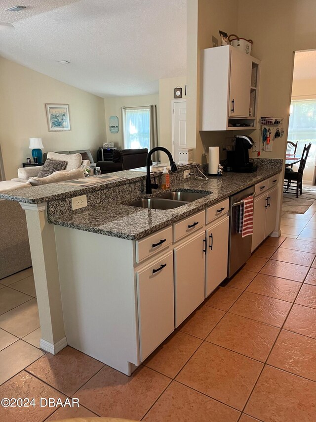 kitchen featuring white cabinetry, sink, dark stone counters, light tile patterned floors, and stainless steel dishwasher