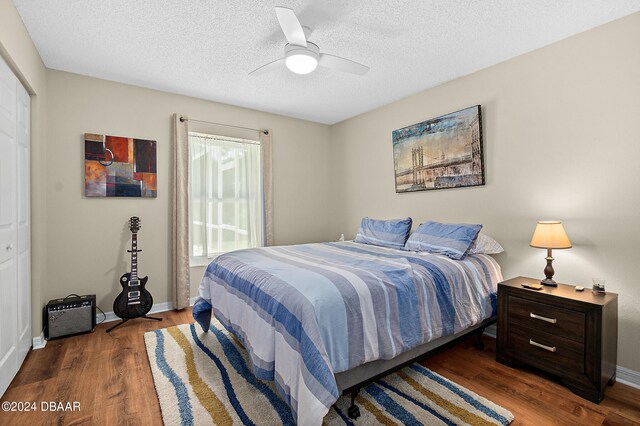 bedroom with dark wood-type flooring, ceiling fan, a textured ceiling, and a closet