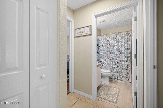 bathroom with toilet, tile patterned floors, curtained shower, a textured ceiling, and vanity