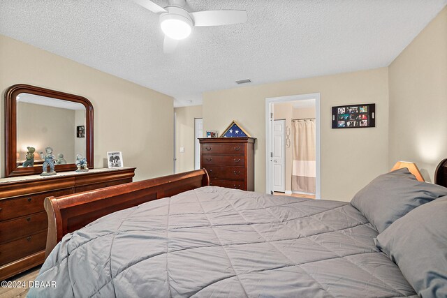 bedroom with a textured ceiling, ceiling fan, and ensuite bath