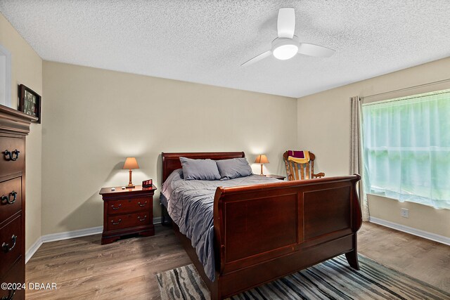 bedroom featuring hardwood / wood-style flooring, ceiling fan, and a textured ceiling