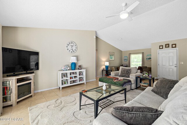 living room with ceiling fan, a textured ceiling, light tile patterned floors, and lofted ceiling