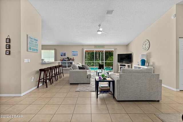 living room with ceiling fan, a textured ceiling, and light tile patterned floors