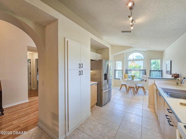 900 Smokerise Blvd, Port Orange, FL 32127 - kitchen with stainless steel fridge, arched walkways, a sink, a textured ceiling, and light countertops