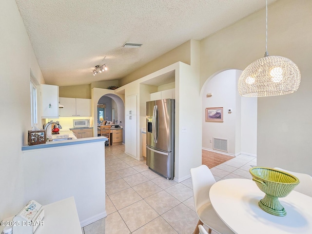 900 Smokerise Blvd, Port Orange, FL 32127 - kitchen featuring stainless steel fridge, arched walkways, light tile patterned flooring, white cabinetry, and a sink