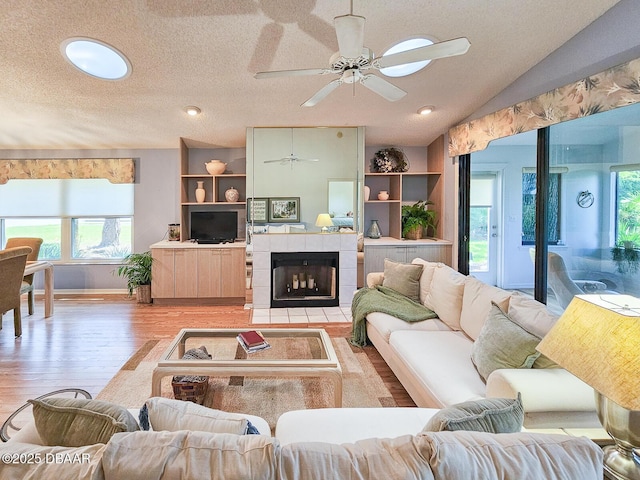 900 Smokerise Blvd, Port Orange, FL 32127 - living room featuring light wood finished floors, a ceiling fan, a textured ceiling, lofted ceiling, and a tile fireplace