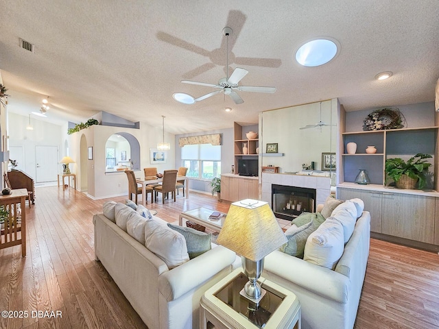 900 Smokerise Blvd, Port Orange, FL 32127 - living area featuring a textured ceiling, ceiling fan, arched walkways, wood finished floors, and vaulted ceiling