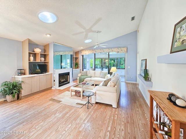 900 Smokerise Blvd, Port Orange, FL 32127 - living area featuring lofted ceiling, a textured ceiling, light wood-style flooring, a fireplace with flush hearth, and ceiling fan