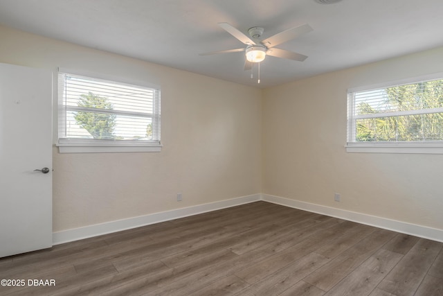 empty room with dark wood-type flooring, plenty of natural light, and baseboards