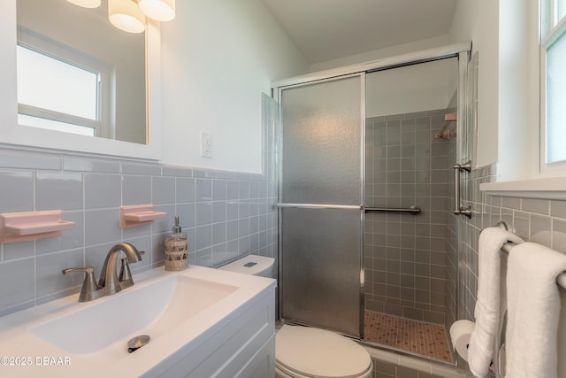 full bathroom featuring a stall shower, vanity, toilet, and tile walls