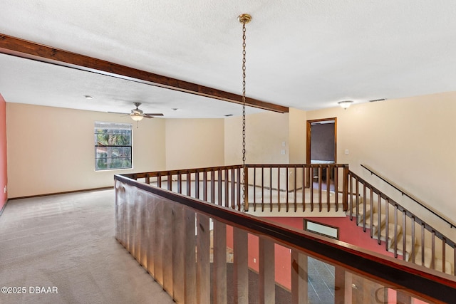 hall featuring an upstairs landing, light colored carpet, a textured ceiling, beamed ceiling, and visible vents