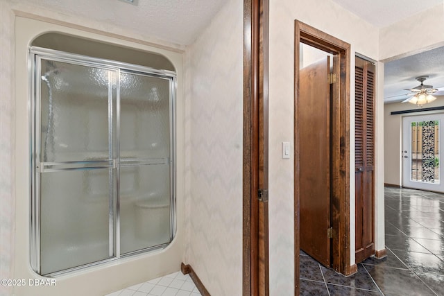 full bath featuring a ceiling fan, tile patterned floors, a stall shower, and a textured ceiling