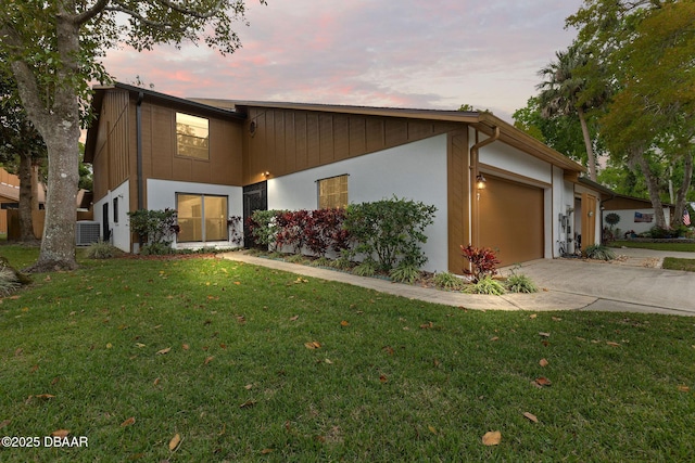 mid-century modern home featuring a lawn, driveway, stucco siding, and a garage