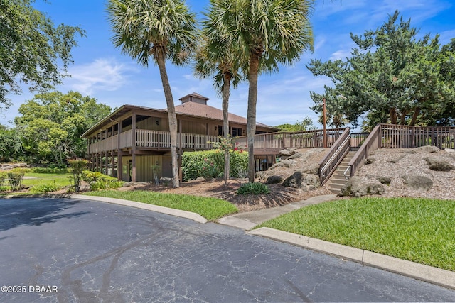 view of side of home with a wooden deck, stairway, a yard, and a chimney