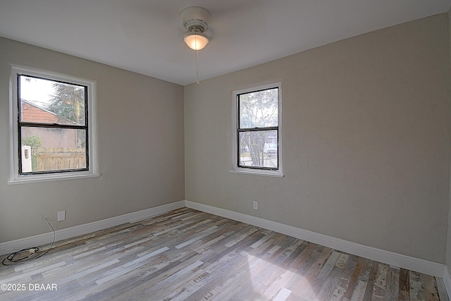 empty room with a ceiling fan, baseboards, and wood finished floors
