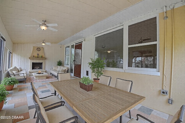 exterior space with a large fireplace, a ceiling fan, and outdoor dining space