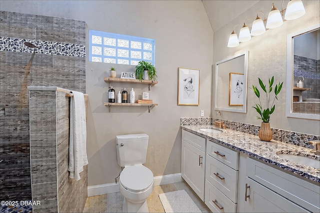 bathroom with toilet, a sink, baseboards, and tiled shower