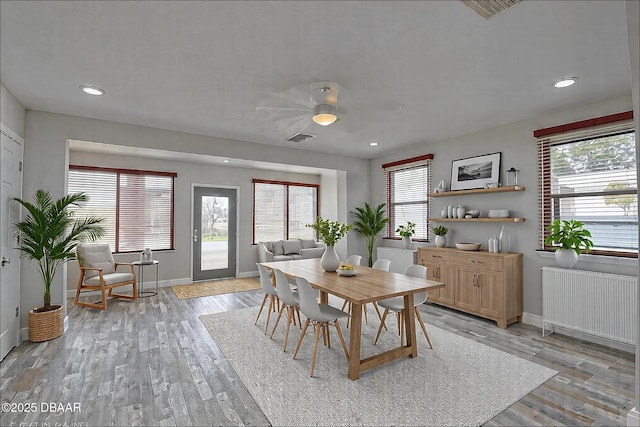 dining space featuring baseboards, visible vents, radiator heating unit, and light wood-type flooring