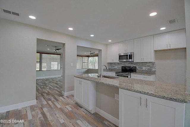 kitchen featuring appliances with stainless steel finishes, sink, white cabinets, decorative backsplash, and light stone counters