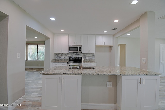 kitchen featuring white cabinetry, light stone counters, range with electric stovetop, and decorative backsplash