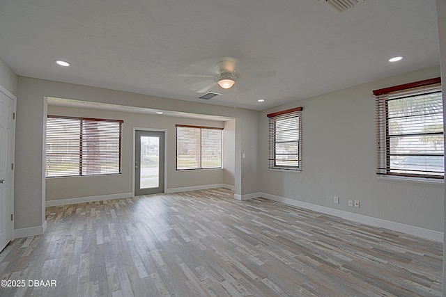 spare room with light wood-type flooring, baseboards, ceiling fan, and visible vents