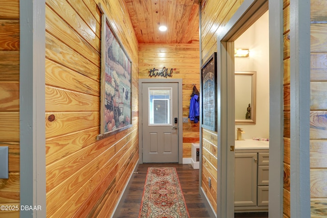 corridor featuring sink, dark wood-type flooring, wooden walls, and wooden ceiling