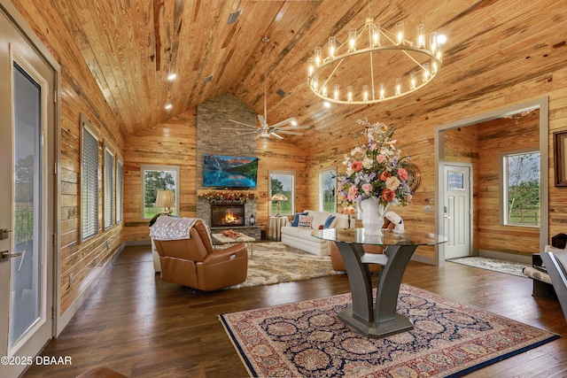 living room with wooden walls, a stone fireplace, high vaulted ceiling, and wooden ceiling