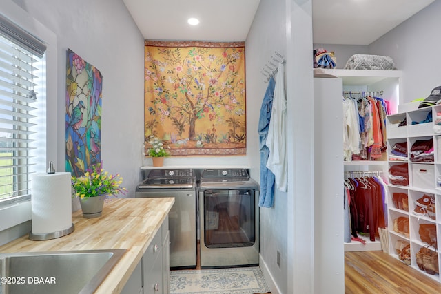 clothes washing area featuring washing machine and clothes dryer and light hardwood / wood-style floors