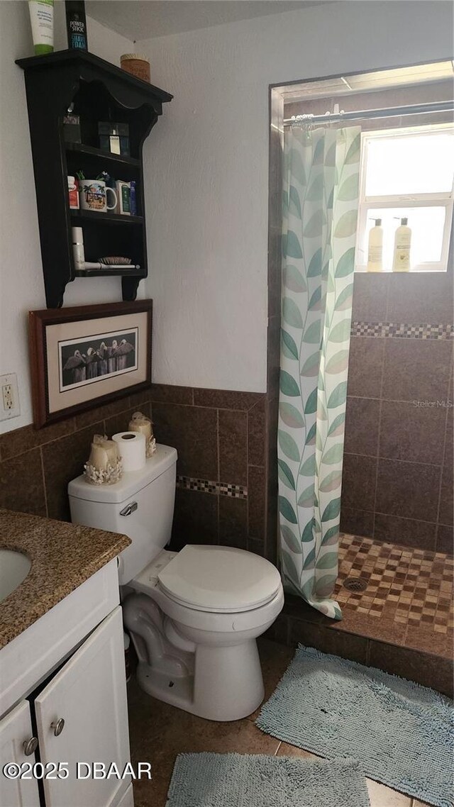 bathroom featuring curtained shower, tile walls, tile patterned flooring, vanity, and toilet