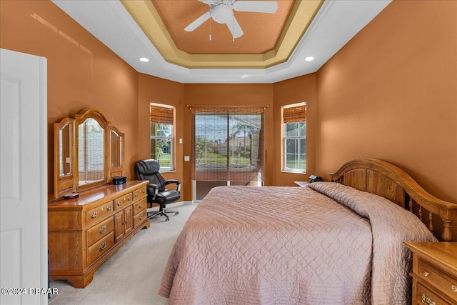 bedroom with a tray ceiling, light carpet, and ceiling fan