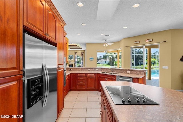 kitchen with kitchen peninsula, appliances with stainless steel finishes, ceiling fan, sink, and light tile patterned floors