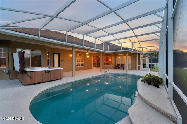 pool at dusk with a patio area, a lanai, and a hot tub