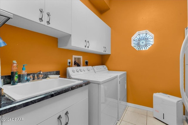 clothes washing area with washer and dryer, light tile patterned flooring, cabinets, and sink