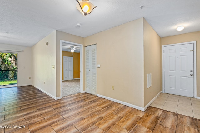 interior space featuring light wood-type flooring, a textured ceiling, and ceiling fan