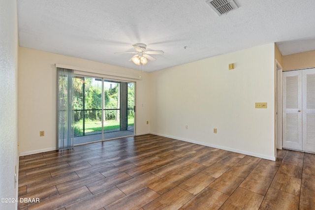 spare room featuring dark wood-type flooring, a textured ceiling, and ceiling fan