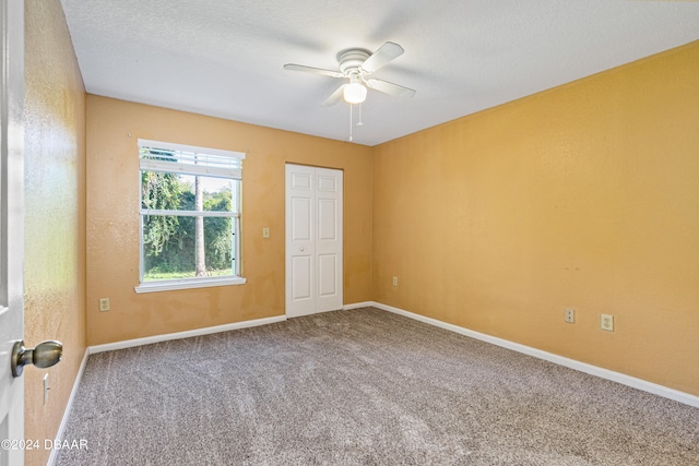 carpeted empty room featuring a textured ceiling and ceiling fan