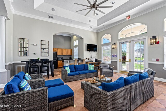 940 Village Trl Unit 6-102, Port Orange, FL 32127 - living room featuring a raised ceiling, a ceiling fan, a high ceiling, crown molding, and decorative columns
