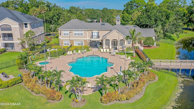 view of pool featuring a water view, a lawn, and a patio