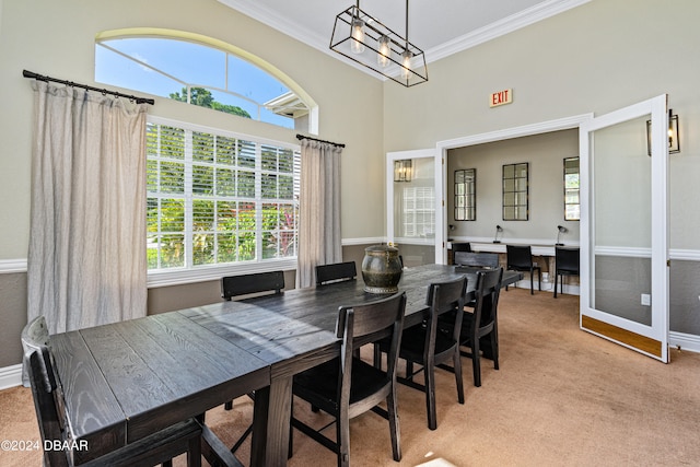 carpeted dining room with a high ceiling and ornamental molding