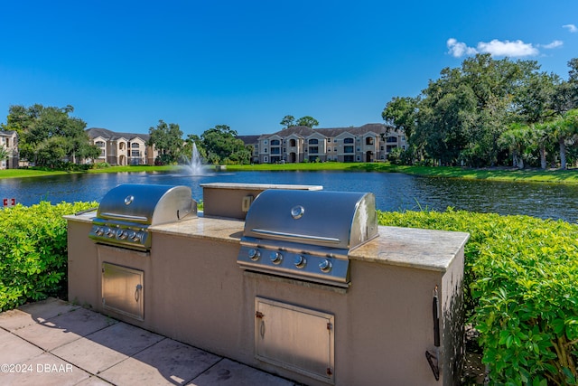 view of patio featuring an outdoor kitchen, area for grilling, and a water view