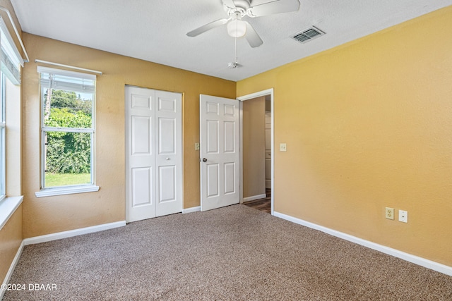 unfurnished bedroom with ceiling fan, a textured ceiling, and carpet flooring