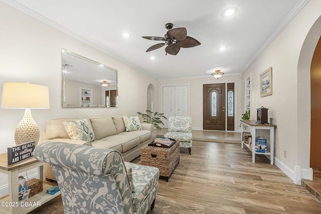 living room featuring hardwood / wood-style flooring, crown molding, and ceiling fan