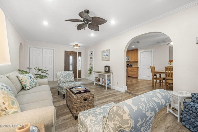 living room with crown molding, ceiling fan, light hardwood / wood-style floors, and built in features