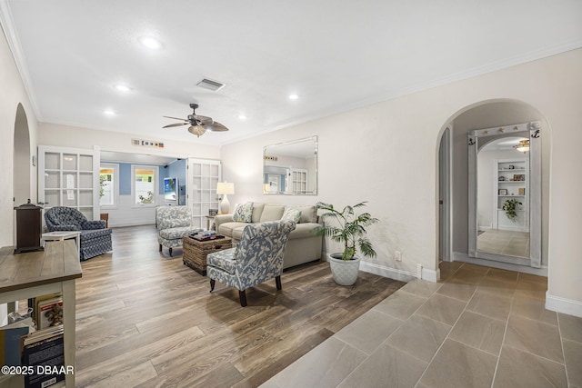 living room with ceiling fan, ornamental molding, built in features, and light wood-type flooring