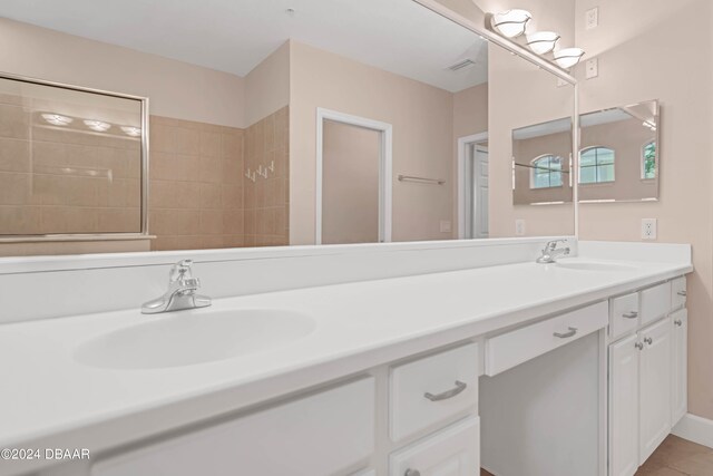 bathroom featuring tile patterned flooring, vanity, and a tile shower